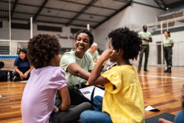 Lady smiling in a gym with two children doing activities