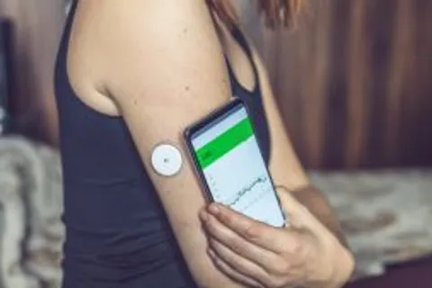 small round sensor place on the arm, with a cell phone next to it with a readout of the sensor