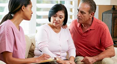 A couple meets with a health care professional in their home.