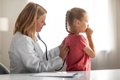 Doctor checking a child patient for a cough