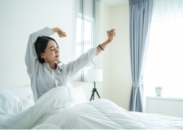 Woman stretching in bed and waking up